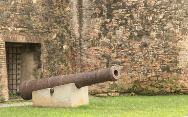 old cannon in front of stone wall