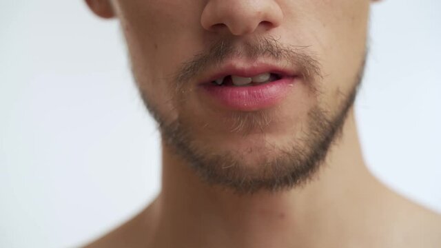 Young European half naked handsome man with thick dark brown beard moustache speak, talk some phrase isolated on white background in slow motion. Close-up portrait of serious guy mouth without clothes
