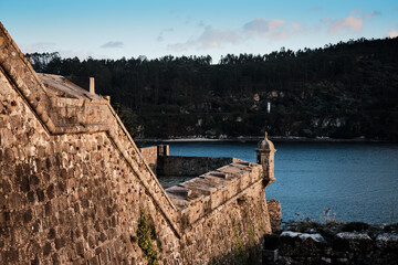 torre de castillo frente al mar con monta&ntilde;as y cielo azul