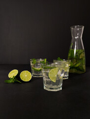 Three glasses of mojito cocktail lemonade with lime and mint on the black background