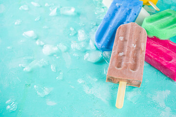 Selection of bright multicolored ice cream popsicle. Various gelato, frozen lollypops - chocolate vanilla blueberry strawberry pistachio orange, with crushed ice on light blue sunny background