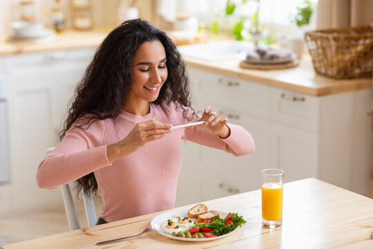 Food Blogger. Young smiling woman taking photo of her brekfast with smartphone - Powered by Adobe
