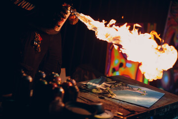 Young street artist finishing his artwork with spray color paint and fire in dark night
