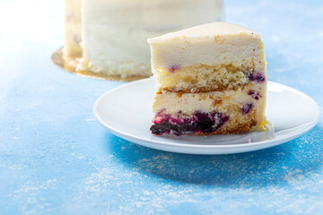 Homemade blueberry cake decorated with white frosting, cream and fresh berries. Birthday or festive cut of piece of sponge pie isolated on white background. Close up,