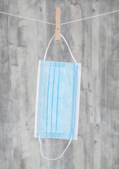 eine Mund-Nasen-Schutz Maske an einer W&auml;scheleine vor einem Hintergrund aus Holz 