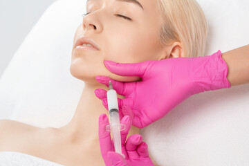 Cosmetologist makes lipolytic injections to burn fat on the chin, cheeks and neck of a woman...