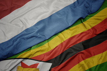 waving colorful flag of zimbabwe and national flag of luxembourg.