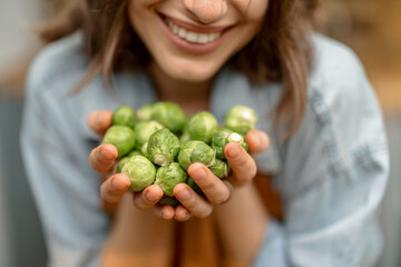 Portrait of pretty woman in apron with fresh brussels sprouts on the kitchen at home. Close up....