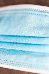 Detailaufnahme einer OP-Maske auf einem Untergrund aus Holz