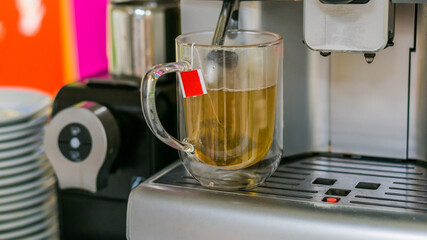 Hot tea from coffee machine in cafe. Steamed from hot water made  in shot glass at cafe.