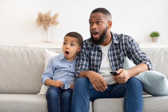 Shocked African Father And Son Watching TV At Home