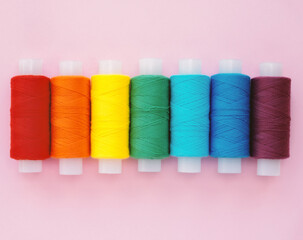 Collection of colored thread layout on a pink background. Handmade and sewing minimal concept.