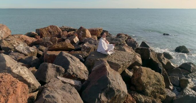 Meditaci&oacute;n saludable de mujer de blanco frente al sol y dron orbitando