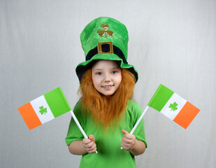Saint Patricks Dayc elebration. Pretty smiling small girl with decorative red beard in green...