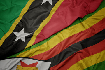 waving colorful flag of zimbabwe and national flag of saint kitts and nevis.