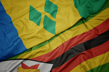waving colorful flag of zimbabwe and national flag of saint vincent and the grenadines.