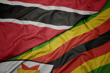 waving colorful flag of zimbabwe and national flag of trinidad and tobago.