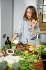 Pretty woman with green ingredients thinking about cooking healthy food on the kitchen. Healthy and wellness concept. High quality photo