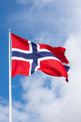 Norwegian flag in wind on blue  and white sky background - 409936546