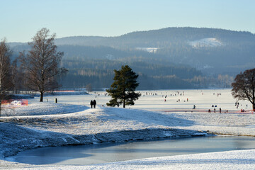 Walking for just the walk is a favorite activity in Norway. Families are gathering at the frozen lake for skating and having fun. It is a cold Sunday in January .