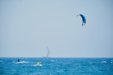 kitesurfing with a sailboat in the background in the Mediterranean