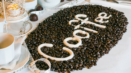 Close-up of coffee beans in the shape of a heart and the inscription coffee on white backgound