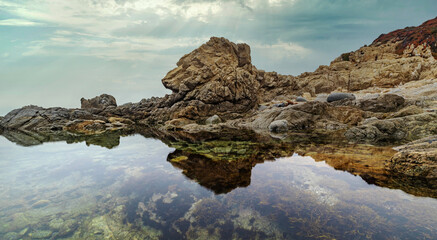 Beautiful seascape, ocean views, rocky coast, sunlight on the horizon. Composition of nature. Sunset scenery background. Cloudy sky. Water Reflection. California Seashore.
