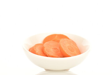 Several slices of ripe organic, unpeeled carrots in a white ceramic saucer, close-up, isolated on white.