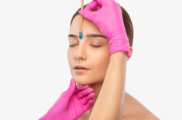 Makeup artist does facial hair removal procedure. Beautiful girl with blue eyes having Permanent...