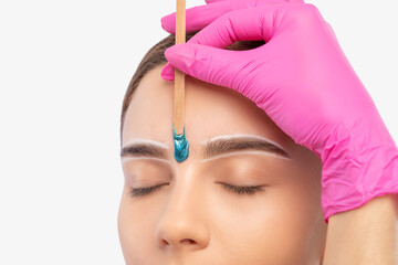 Makeup artist does facial hair removal procedure. Beautiful girl with blue eyes having Permanent...