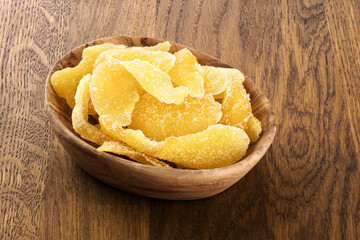 Dried ginger with sugar on wooden background.