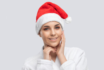 Portrait of a beautiful brunette girl in santa hat with healthy clean skin and fresh make-up. Aesthetic cosmetology and makeup concept.