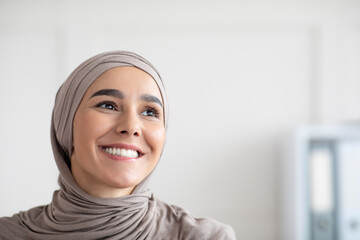 Joyful arab woman in hijab looking at copy space