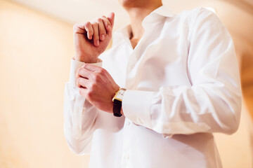 Obraz premium man fastens the cuffs on his white shirt. Close