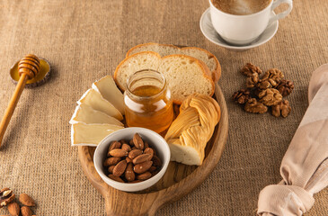 Healthy breakfast with honey, cheese, almonds, loaf. A healthy combination of products against a textured sackcloth background
