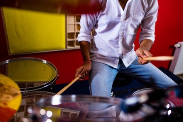 indian man playing the drums sticks close-up in recording studio