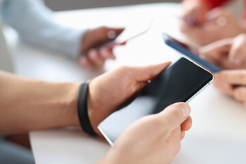 Group of people holding mobile phones at table closeup