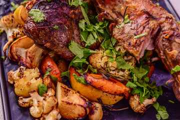 Juicy roasted leg of lamb with fruits and vegetables on tablecloth background