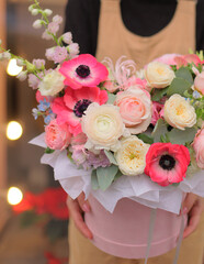 Floral bunch in round box. Bouquet in bright color of beautiful Mixed flowers. Excellent garden flowers in the arrangement , the work of a professional florist. Gift box in florist hands