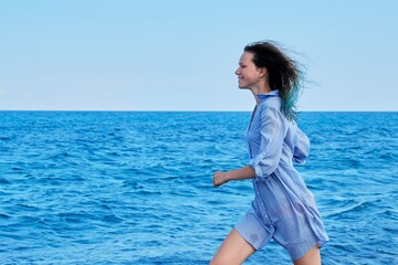 Beautiful young woman running on sea beach