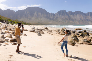 African american couple taking photos on a beach by the sea
