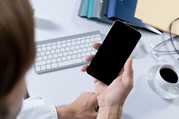 Over shoulder view of caucasian male doctor making consultation video call using smartphone