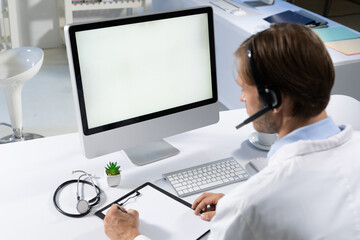 Caucasian male doctor making consultation video call using computer and headset