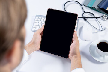 Over shoulder view of caucasian male doctor making consultation video call using tablet