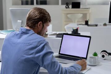 Caucasian businessman sitting at desk using laptop in an empty office