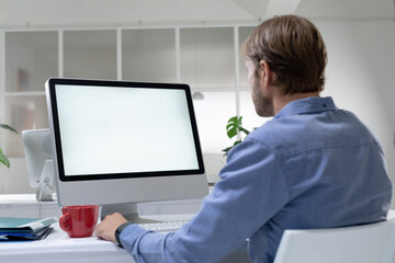 Rear view of caucasian businessman sitting at desk making video call using desktop computer
