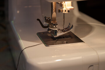 The sewing machine's foot with a needle sews purple fabric. Empty space for text
