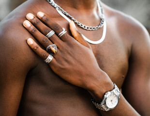Unrecognizable crop African American male with naked torso showing hand with trendy silver rings
