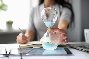 Business woman putting hourglass on digital tablet closeup - obrazy, fototapety, plakaty
