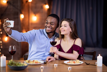 Happy Interracial Couple Taking Selfie On Smartphone During Romantic Date In Restaurant